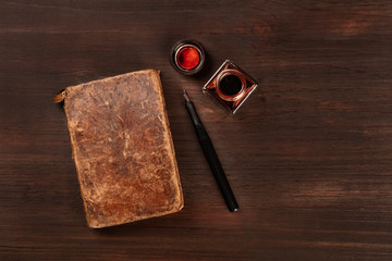 An old journal with a nib pen and an ink well, shot from the top on a dark wooden background with a place for text