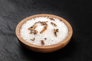A bowl of sea salt infused with truffle shavings on a black background with copy space