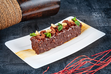 Close up view on slice of white cake with nuts and mint on dark backfround. Dessert food for breakfast. Served ready to eat sweets. Copy space for text