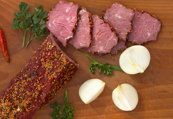 Smoked beef with pieces and spice, bulb onion, parsley, red pepper on wooden table