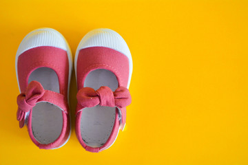 Pink shoes for children isolated on a yellow background.