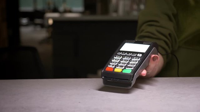 Close-up shot of person using terminal and credit card performing contactless payment.