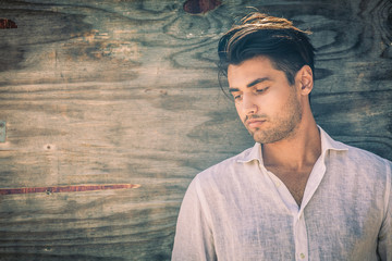 Profile portrait of thoughtful and handsome man on wooden background. He is wearing a white shirt and has a light beard. Look down. © angelocordeschi