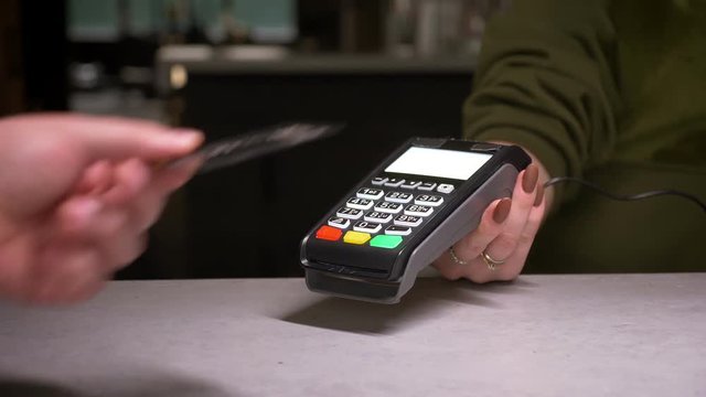 Close-up shot of person using terminal and credit card performs contactless payment and prints the check.