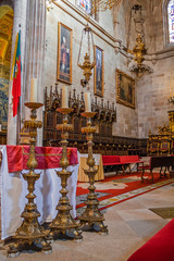 Braga, Portugal - December 28, 2017: Se de Braga Cathedral. Three tall candlesticks in main chapel altar and choir stalls. Oldest Cathedral in Portugal. 11th century Romanesque, with Gothic Baroque