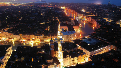 Aerial night shot of iconic illuminated Ponte Rialto or Rialto bridge crossing Grand Canal, Venice, Italy
