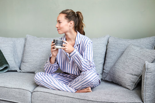 Pretty brunette in pj's on sofa with morning coffee