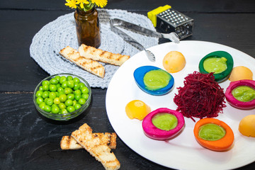 Multicolored egg white filled with pea puree. Grated bead. Green peas in a transparent bowl, all on a black background. 