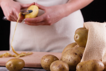 A young woman in an apron peeling potatoes