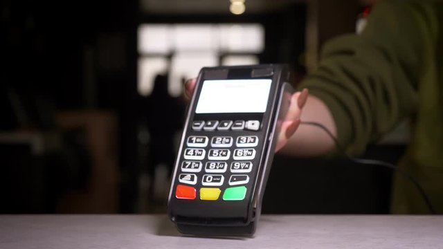 Close-up shot of man applies smartphone to terminal performing successful contactless payment.