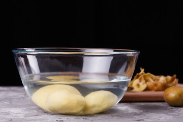 A young woman in an apron peeling potatoes