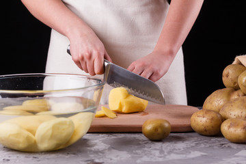young woman in an apron cuts potatoes
