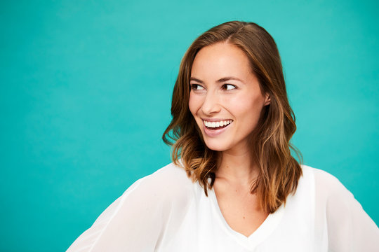 Smiling brunette woman in blue studio, looking away