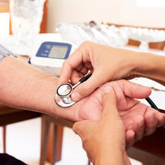 Fototapeta premium doctor measuring the blood pressure of a senior