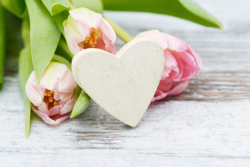 white Heart with pink flowering  tulips on wood