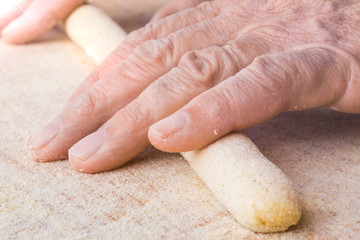 Mani di un uomo stanno facendo gli gnocchi di patate fatti in casa con farina integrale su un...