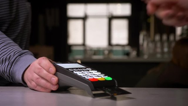Close-up shot of woman inserts credit card into terminal performing paypass payment.