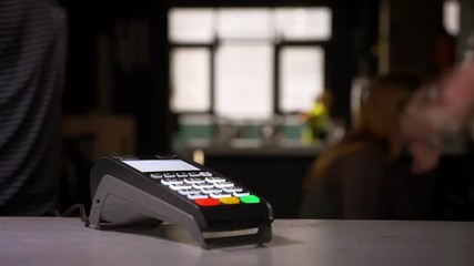 Close-up shot of female hand enters the pin code on terminal performing payment on gym background. - Powered by Adobe