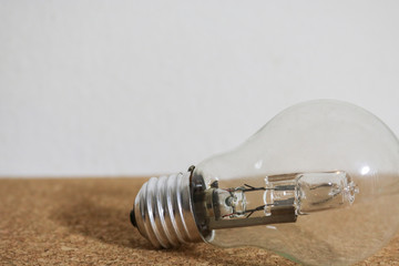 Una lampadina appoggiata su un fondo di sughero con lo sfondo bianco