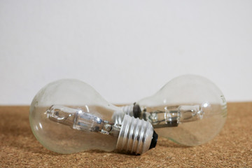 Due lampadine appoggiate su un fondo di sughero con lo sfondo bianco