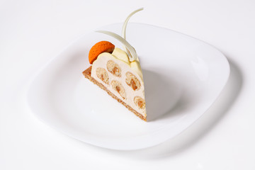 Slice of the contemporary version of the famous french Saint Honore Cake, decorated with choux bun with craquelin - (crispy cream puff), covered with yellow velvet spray, on white plate, on white back