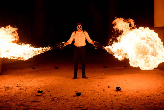 Halloween man in costume with flamethrower in his hands. Devil makeup on face