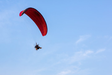 Adventure man active extreme sport pilot flying in sky with paramotor engine glider parachute. Paramotor flying on the sky at sunset. 