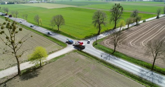 Drone shot of traffic on x shaped crossroad on countryside. Driving cars, trucks, buses on intersection.