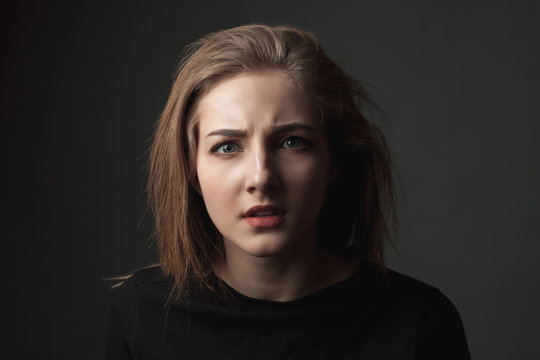 Puzzled young woman on the black background