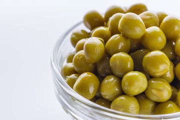 canned green peas in a glass bowl on a white background