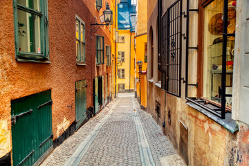 Fototapeta na wymiar The narrow cobblestone street with medieval houses of Gamla Stan historic old center of Stockholm at summer sunny day.