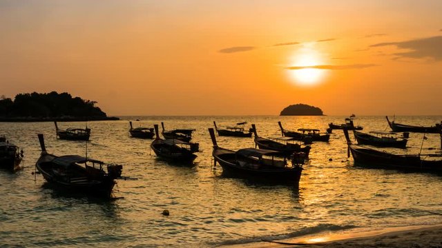 Time-lapse silhouette boats over sea at Koh Lipe during sunrise, sun moviing up , Zoom out.