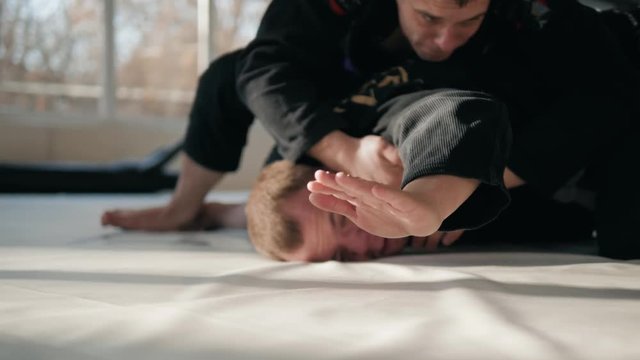 Concept of defeat, loss. Martial artist hand wearing mix mma open fingers gloves touching the tatami gym mats resembling tiredness, defeat, fatigue, exhaustion surrender surrend jiu jitsu boxing.