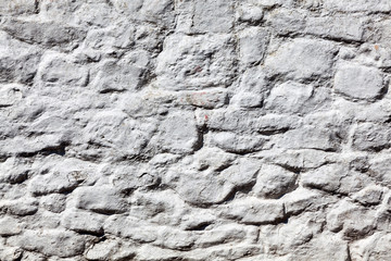 Old grey white weathered rough stone wall texture background