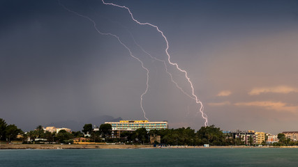 Naklejka na ściany i meble Thunderstorm with several lightning strikes over Denia on the Costa Blanca, photographed from the shore of Las Rotas.