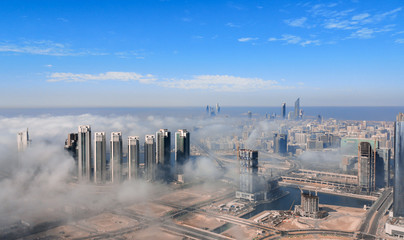 Aerial view of Abu Dhabi city skyline, famous towers and skyscrapers surrounded by fog clouds in the morning