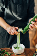 Female chef peeling skin of a cucumber