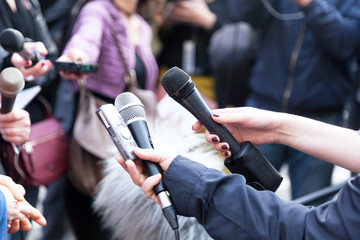 Journalists holding microphones at press conference