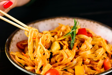 rice noodles with vegetables hanging from chopsticks