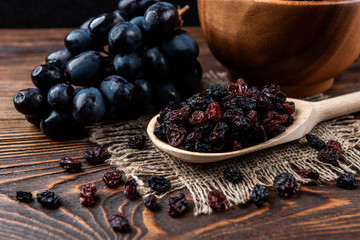 Raisin and grapes on dark wooden background.