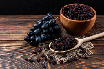 Raisin and grapes on dark wooden background.