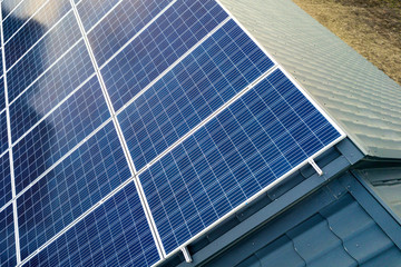 Obraz premium Aerial top view of new modern residential house cottage with blue shiny solar photo voltaic panels system on roof. Renewable ecological green energy production concept.
