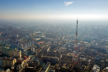 Naklejka premium Aerial view of modern city urban foggy landscape with tall television tower on bright blue sky copy space background at dawn. Drone photography.