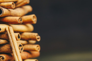 tower of whole sticks of fragrant cinnamon on a wooden rural table. copyspace. composition of seasoning and slide flavoring aromatic spice. close-up. side view, macro