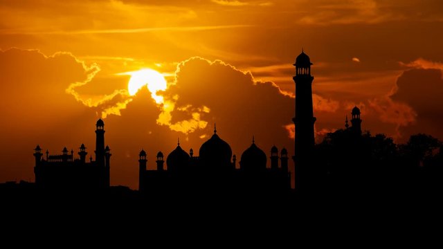 Badshahi Mosque: Time Lapse at Sunset with Red Sun and Clouds, one of the largest Mosques in the World, Lahore, Pakistan
