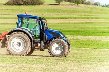 Blue tractor in the field. Working on an agricultural farm in the Czech Republic. Spring work in agriculture.