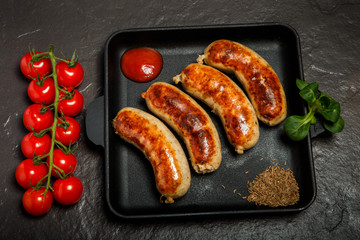 top view square pan with four sausages, ketchup and caraway