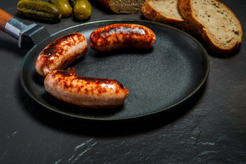 closeup appetizing ruddy juicy sausages fried in large frying pan