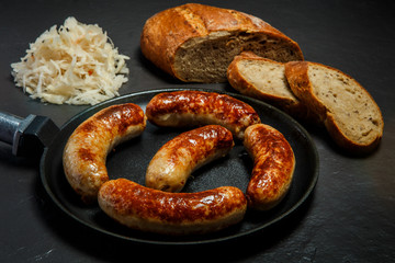 five appetizing ruddy juicy sausages fried in large pan