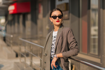 Shot of happy smiling brunette woman wearing modern clothes walking in the city in sunny spring day